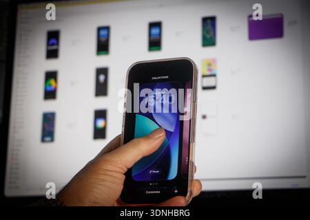 Person holding an iphone 17 smartphone showing customization options against a display of mobile app icons Stock Photo