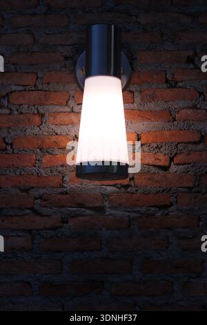 Modern exterior wall sconce illuminating red brick texture at night with warm glow. Stock Photo