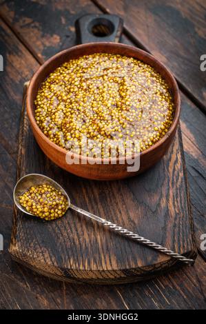 Dijon French mustard with grainy texture in wooden bowl flat lay on wooden background with copy space. Stock Photo
