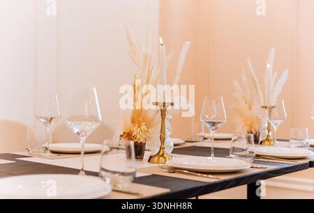Elegant restaurant table setting with candle and pampas grass centerpiece Stock Photo