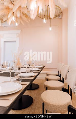 Elegant banquet table set with wine glasses, candles and pampas decor Stock Photo