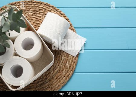 Toilet paper rolls in box and eucalyptus on blue wooden table, flat lay. Space for text Stock Photo