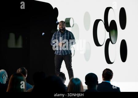 African american senior designer introducing new smartphone to attendees during business summit panel discussion. Electronics product presentation with reveal of new mobile device launch. Stock Photo