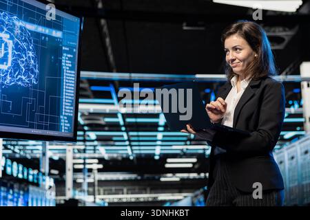Jolly server room software developer using AI feeling happy by upgraded cloud storage gear increased performance. Smiling data center admin pleased by artificial intelligence processing large datasets Stock Photo