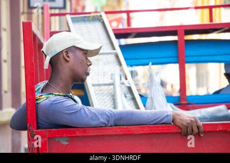 Young hispanic worker man wearing a baseball cap rests on the side of a rpick up truck in havana cuba Stock Photo