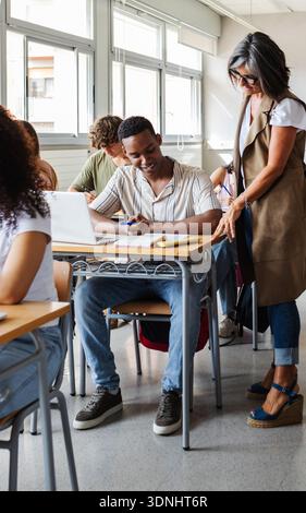 Teacher helping student with studies during classroom lesson Stock Photo