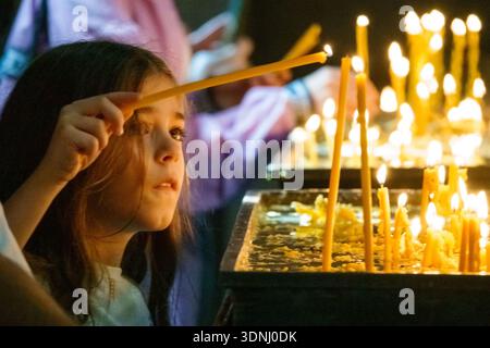 A girl lights candles in Etchmiadzin Cathedral, Vagharshapat, Armenia. Stock Photo