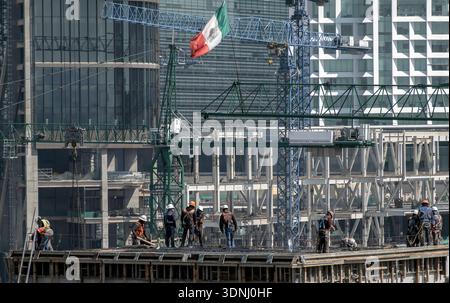 Construction workers on a building site with cranes and a Mexica flag in Mexico City, Mexico Stock Photo