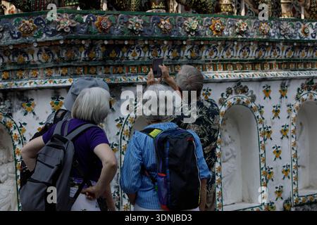 Senior backpackers taking a photograph with smartphone and exploring at Thai temple, rear view, at Wat Arun. Stock Photo