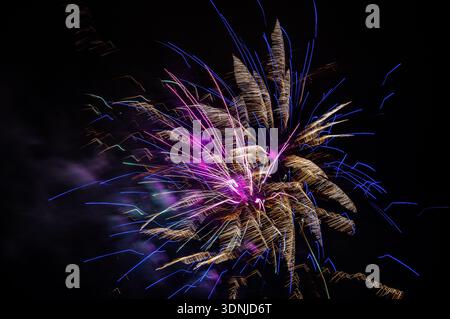 Vibrant fireworks explosion at night: Long exposure captures colorful bursts and radiating trails against deep black sky, no stars visible. Stock Photo