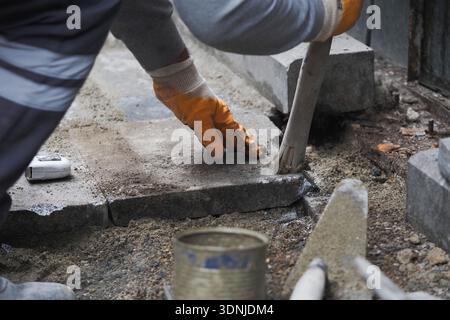 Construction worker lays stone pavement in city street Stock Photo