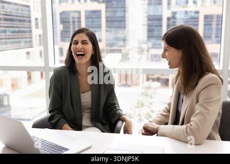 Businesswomen laughing, enjoy friendly work relations, having fun during break Stock Photo