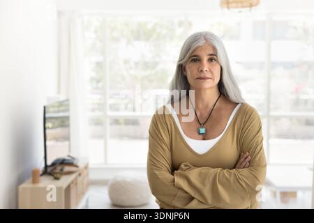 Middle-aged woman standing confidently in modern, well-lit room Stock Photo
