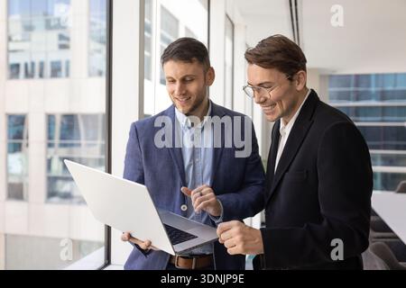 Two businessmen dressed in suits looking at laptop screen Stock Photo