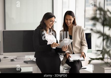 Two diverse women engaged in workflow using tablet Stock Photo