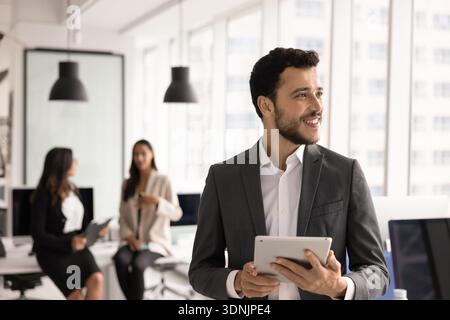 Happy Arabic businessman, department head stands in coworking with tablet Stock Photo