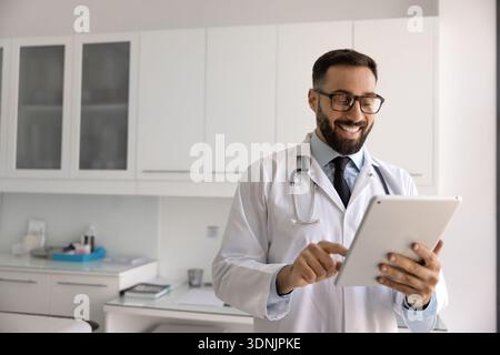 Smiling male doctor giving remote consultation online using digital tablet Stock Photo