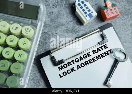 Concept of mortgage rate lock agreement write on clipboard isolated on Wooden Table. For loan documents, financial planning and home financing protect Stock Photo