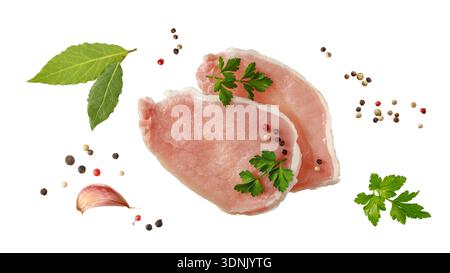 Raw pork meat steaks with parsley and pepper isolated on white background. Pork filet pieces for baking, grilling and barbecue. Stock Photo