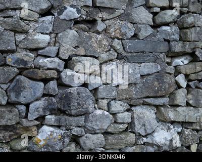 Weathered limestone dry stonewall texture with natural stone detail. Stock Photo