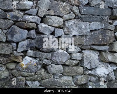 Weathered limestone dry stonewall texture with natural stone detail. Stock Photo