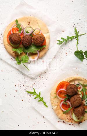 Baking paper of delicious pitas with falafel and fresh vegetables on white background Stock Photo