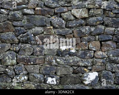 Old exterior dry stone wall with subtle mineral staining. Stock Photo