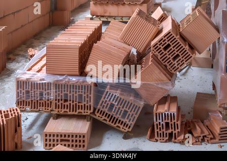 Broken pallet of red clay bricks on a construction site. Collapsed building materials due to storage error or accident. Concept of workplace safety, w Stock Photo