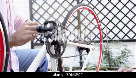 Fixing man in light pink long-sleeve shirt and blue-jeans turning crankset using wood rod on patio Stock Photo