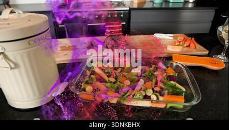 Preparing rectangular glass baking dish with chopped veg on dark kitchen countertop, magenta haze Stock Photo