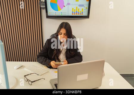 Professional woman concentrating on a mobile phone during work in an office setting Stock Photo