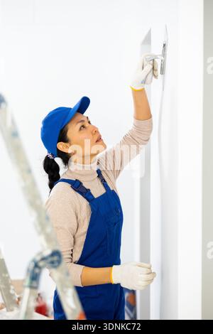 Woman applying plaster with floated trowel Stock Photo