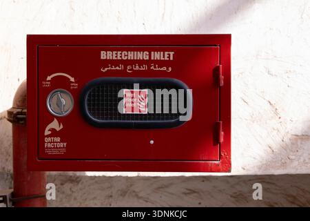 Doha, Qatar - January 25, 2026: Red fire nozzle box mounted on wall with glass front panel, containing fire hose reel for emergency use Stock Photo