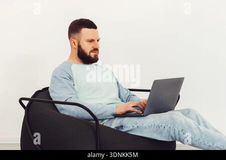 Man Using Laptop Computer Working Online Sitting In Chair Indoors Stock Photo
