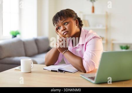 Tired Or Bored African American Woman Working On A Laptop At Home Stock Photo