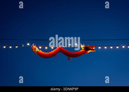 Colorful Chinese dragon decoration shining brightly between festival lights in the night sky Stock Photo