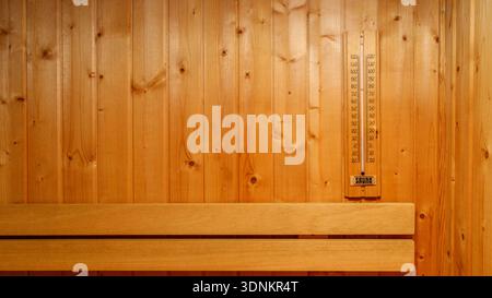 Wooden wall with thermometer in the sauna room. Traditional finnish sauna interior detail. Stock Photo