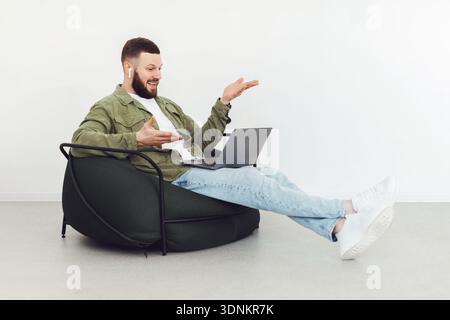 Freelancer Guy Video Calling Via Laptop Wearing Earbuds At Home Stock Photo