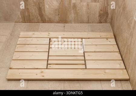 Wooden shower mat on tile floor in cabin in bathroom. Home accessories Stock Photo