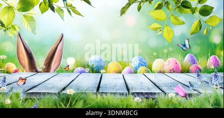 Easter Eggs On Table In Spring Green Garden - Ears Bunny Hidden Stock Photo