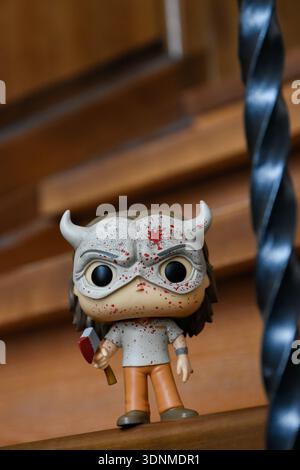 Funko Pop action figure of serial murderer the Grabber from supernatural horror film The Black Phone. Creepy doll in mask with bloody axe on stairs. Stock Photo