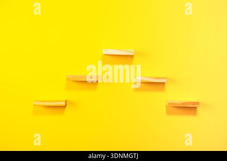 colored wooden clothespins on yellow background Stock Photo
