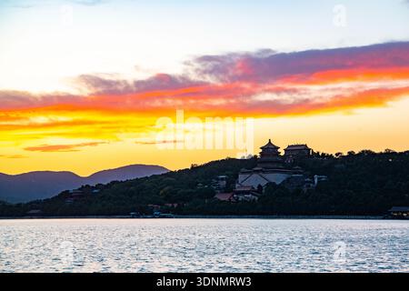 Sunset over the Summer Palace in Beijing, China, with the Tower of Buddhist Incense silhouetted against a dramatic red and orange sky. Stock Photo
