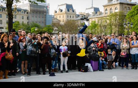 PARIS, FRANCE - MARCH 29, 2014: Unidentified young man doing backflip while dancing breakdance before the public on the street. Dozens artists perform Stock Photo