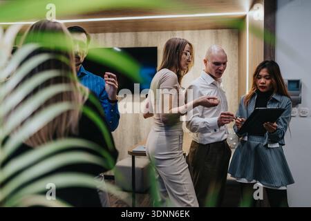 Group of professionals discussing a project in a modern office setting with tablet and documents Stock Photo