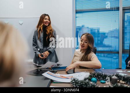 Bright office scene with two colleagues discussing documents during a holiday season meeting Stock Photo