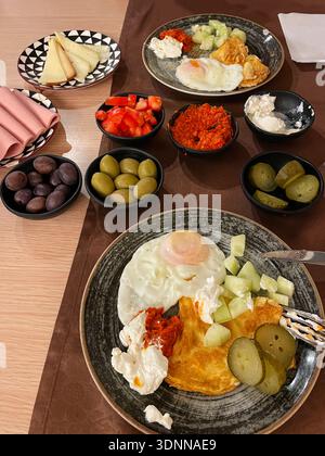 Traditional Turkish breakfast plate with fried egg, omelette, cheese, cucumber, pickles, and red pepper spread. Warm morning meal served on a ceramic Stock Photo