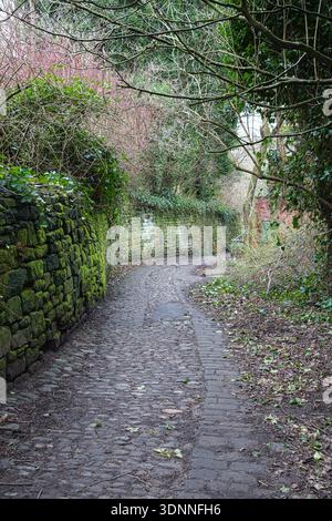 Old Cobbled Path and Mossy Stone Walls Leading Through the Grounds of Rock Hall, Bolton, UK Stock Photo
