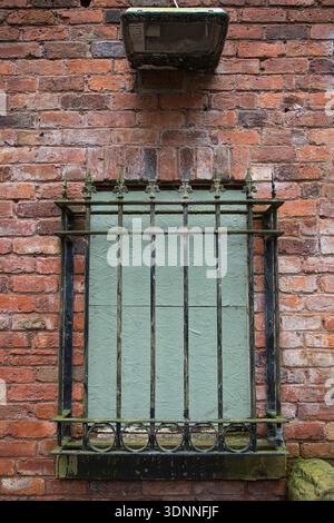 Boarded up Window and Iron Security Bars on Red Brick Building Stock Photo