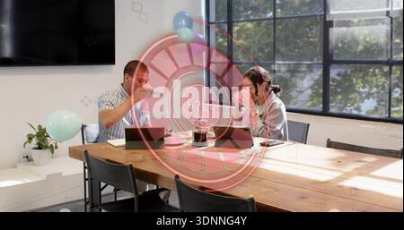 Chatting two staff in striped top light sweater holding mugs using tablets in office with balloons Stock Photo